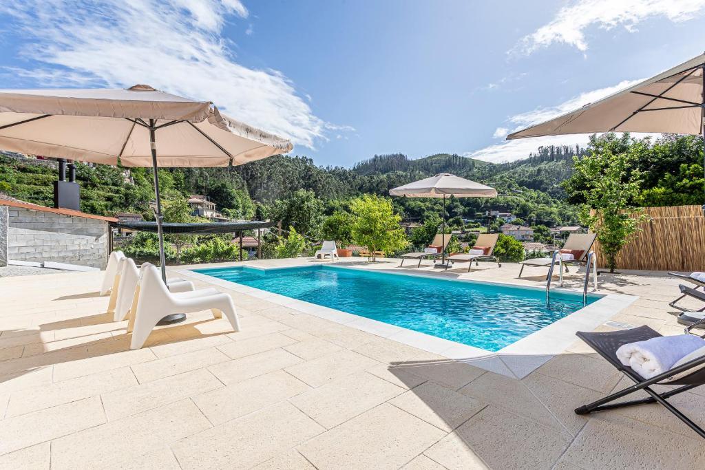 a swimming pool with two umbrellas and chairs next to a pool at Casa Manecas by Hostiva in Reriz