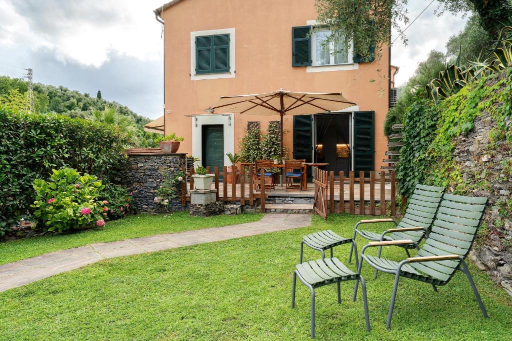 a house with chairs and an umbrella in the yard at Casa Due Ulivi in Lavagna