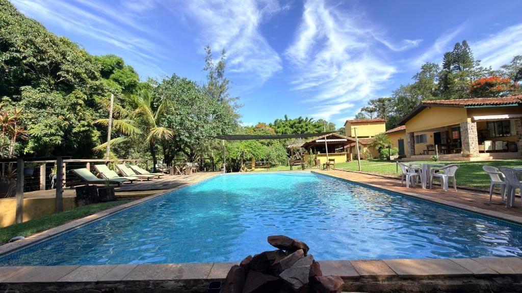 a swimming pool with chairs and a house at Hospedagem Fazenda Nova América in Brotas