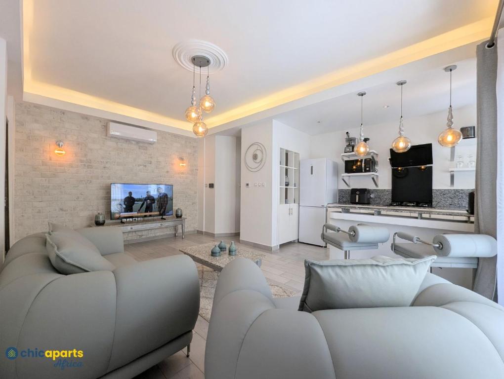 a living room with two couches and a kitchen at Chic apart with parking and balcony in Yaoundé