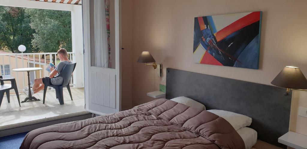 a bedroom with a bed and a woman sitting on a balcony at Les Chênes Verts in Saint-Savinien