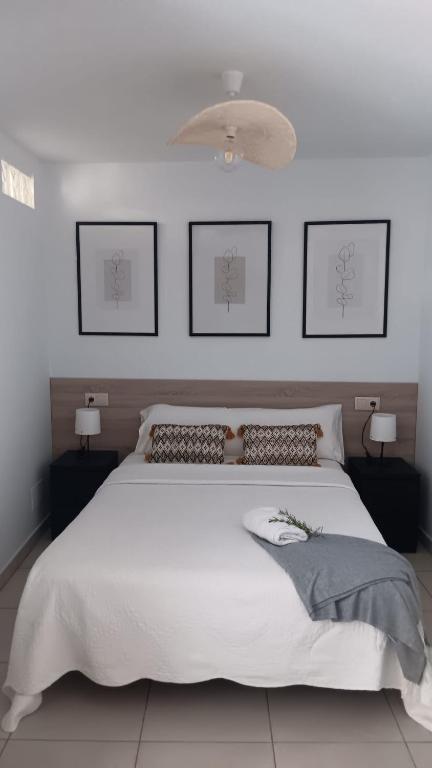 a bedroom with a white bed and two pictures on the wall at Areos de Cabío in A Pobra do Caramiñal