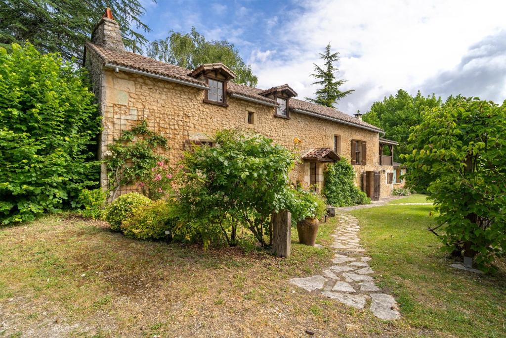 an old brick house with a tree in front of it at Maison Les Rocailles in Saint-Martin-des-Combes
