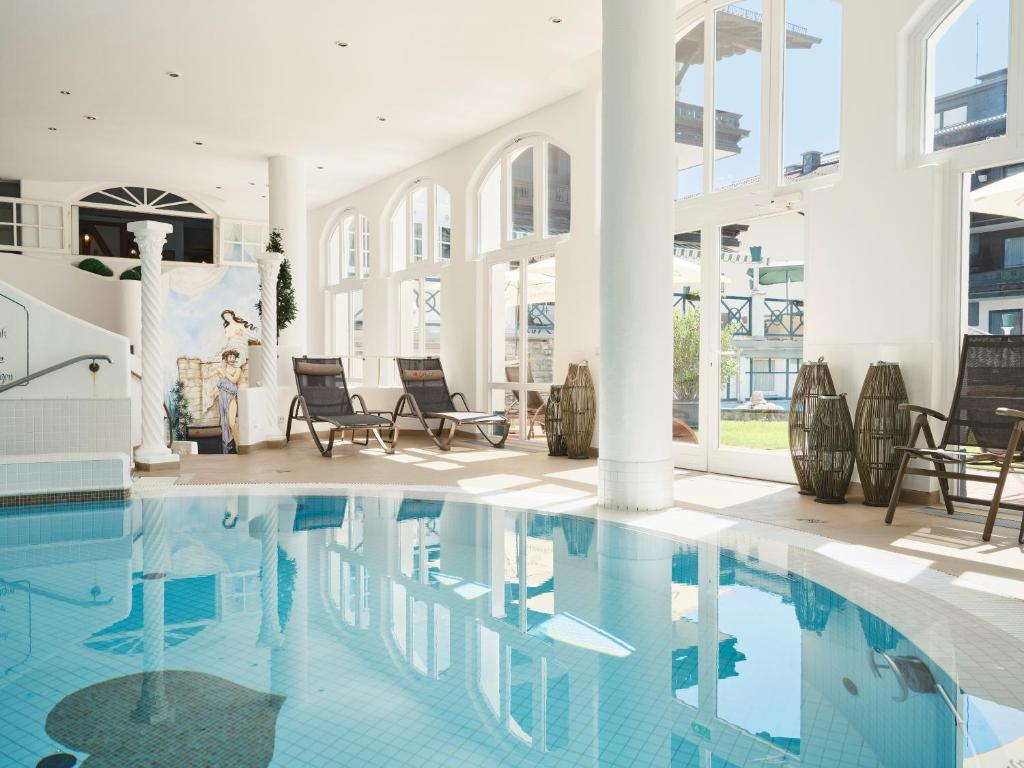 a swimming pool in a building with chairs and tables at Genuss - und Vitalhotel Moisl in Abtenau
