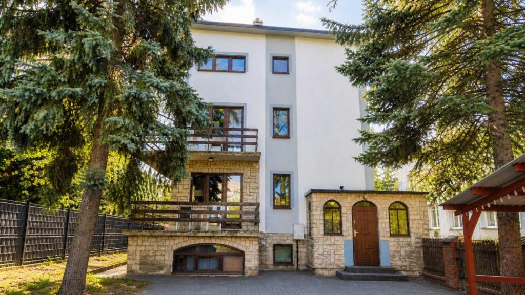 a large white house with a gate and trees at For rest Hostel in Lublin