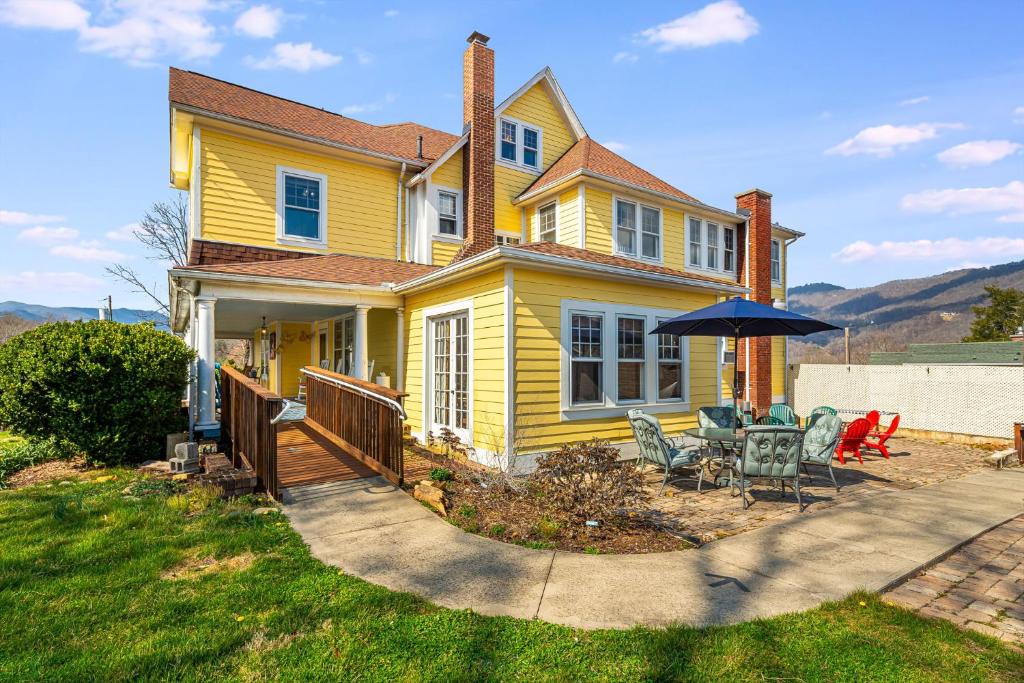 a yellow house with a patio with chairs and an umbrella at Prospect Hill on Main in Waynesville
