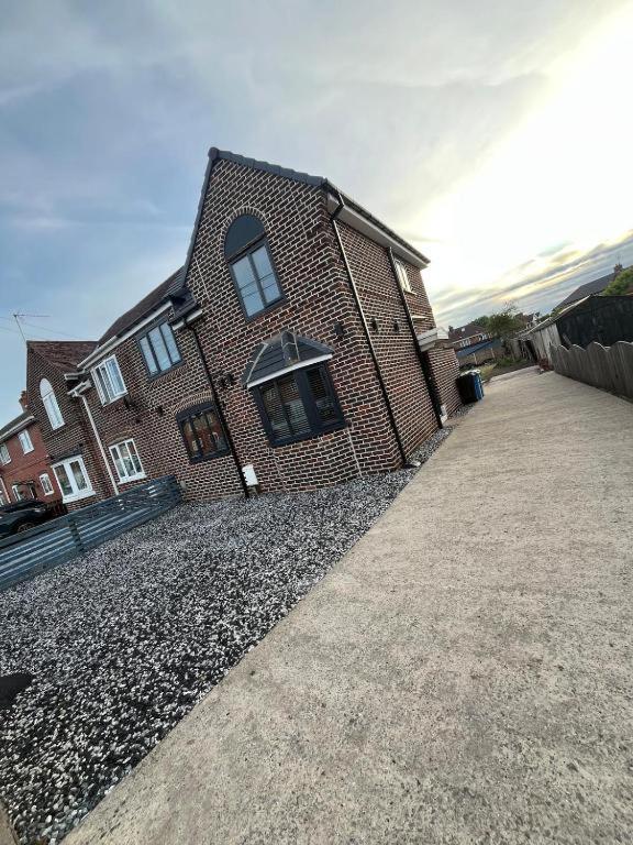 a brick house with a gravel driveway in front of it at Droversdale Delux hottub and pool table in Bircotes