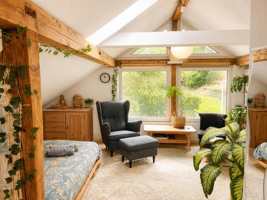 a room with a bed and two chairs and a table at Old Farmhouse Loft near Vaduz in Sevelen