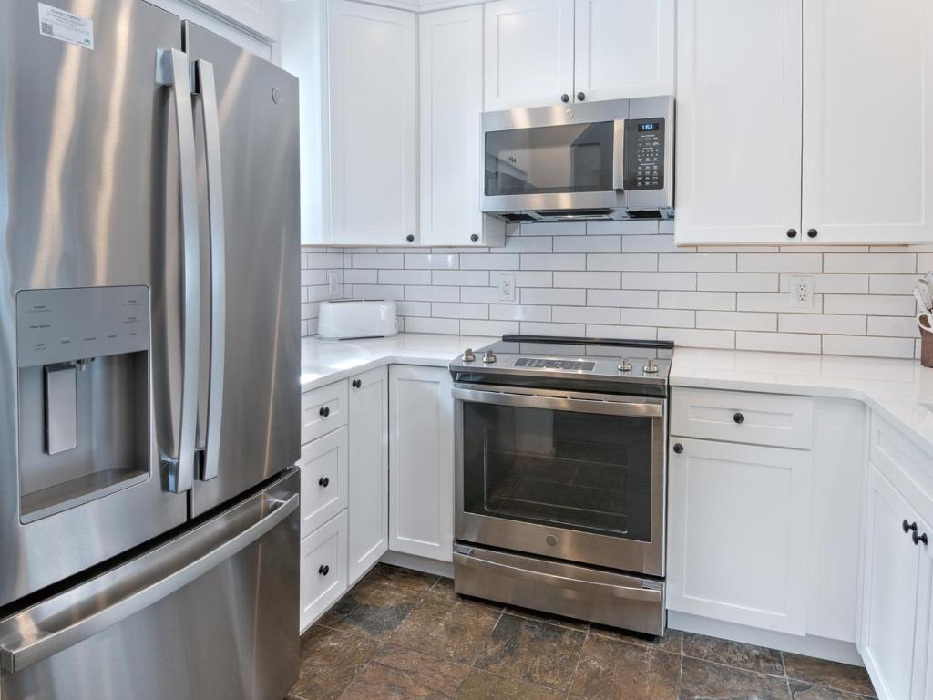 a kitchen with white cabinets and stainless steel appliances at Ptarmigan Townhomes 30 in Vail