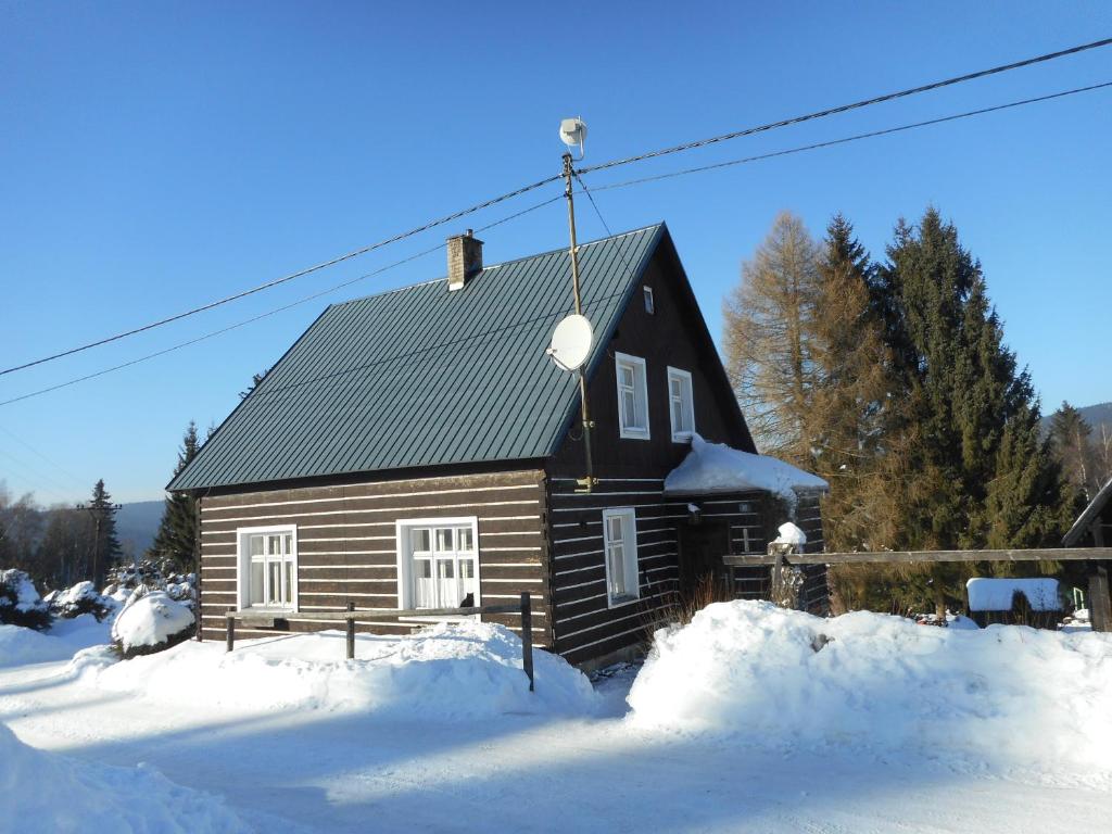 a log cabin with snow in front of it at Chata Pilka in Nové Hamry