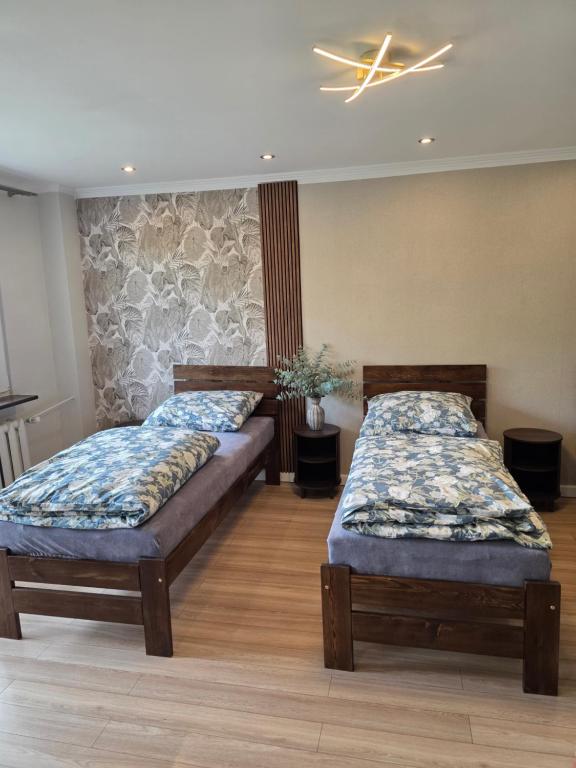 two beds sitting in a room with wooden floors at Apartament dla 7 osób in Głogów