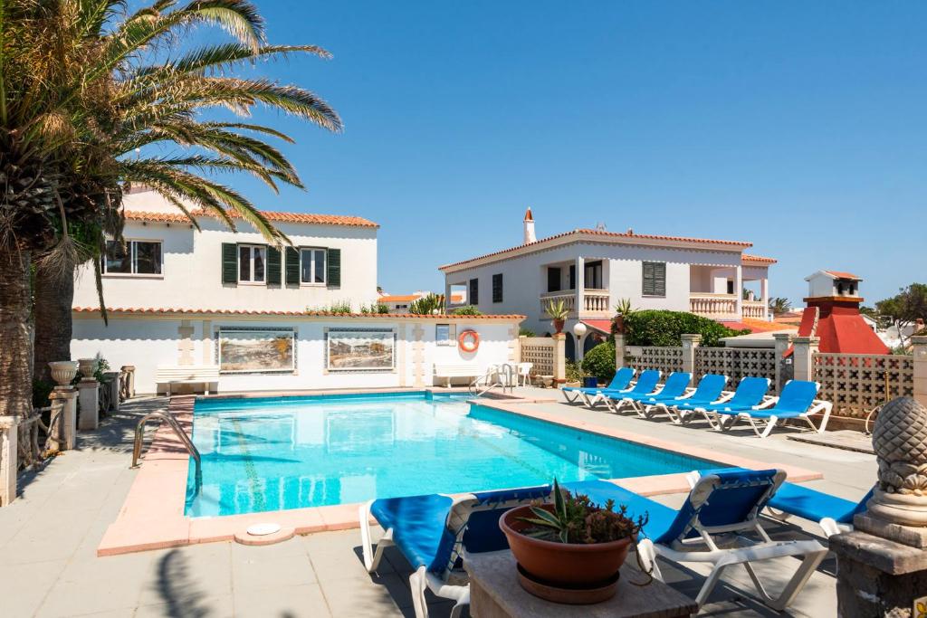 a swimming pool with chairs and a house at Las Belisas in Arenal d'en Castell