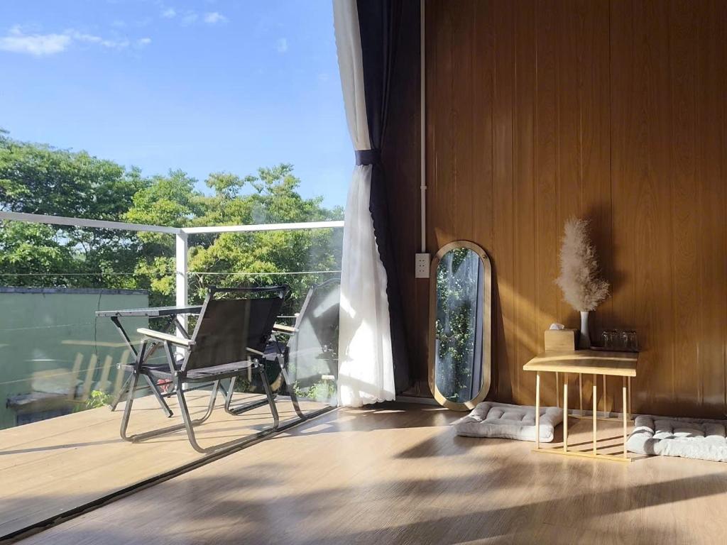 a balcony with a chair and a table and a window at La An Homestay in Vĩnh Hy