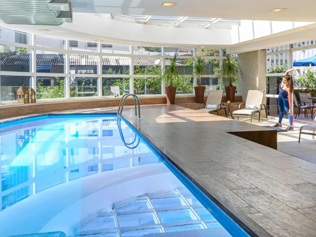 a pool in a hotel with a woman standing next to it at Mercure Sao Paulo Jardins in São Paulo
