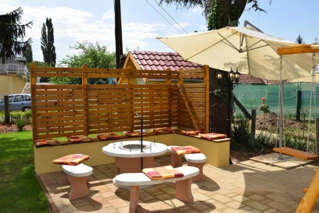a patio with a table and benches and an umbrella at Nóra Wellness nyaraló in Ábrahámhegy