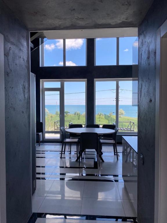 a dining room with a table and chairs and windows at SEALEO in Gribovka
