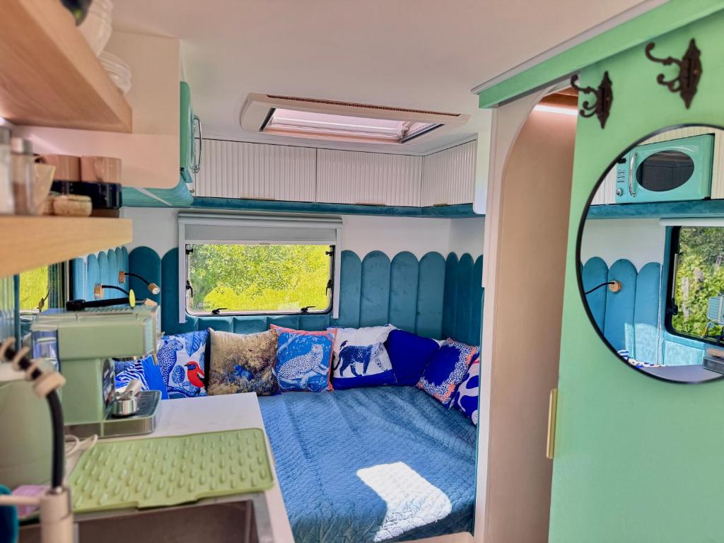 a living room in a rv with a blue couch at Boho luxury caravan in Kisapáti