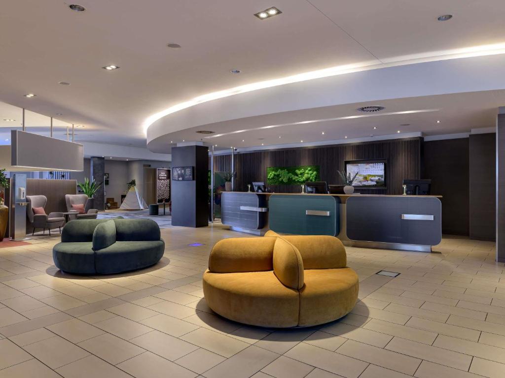 a hotel lobby with two chairs and a bar at Novotel Aachen City in Aachen