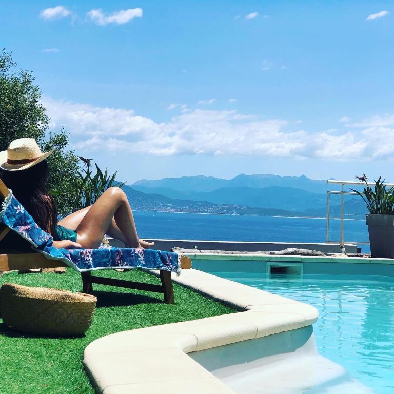 a woman sitting in a chair next to a swimming pool at Les Villas MarInCelu in Porto Pollo