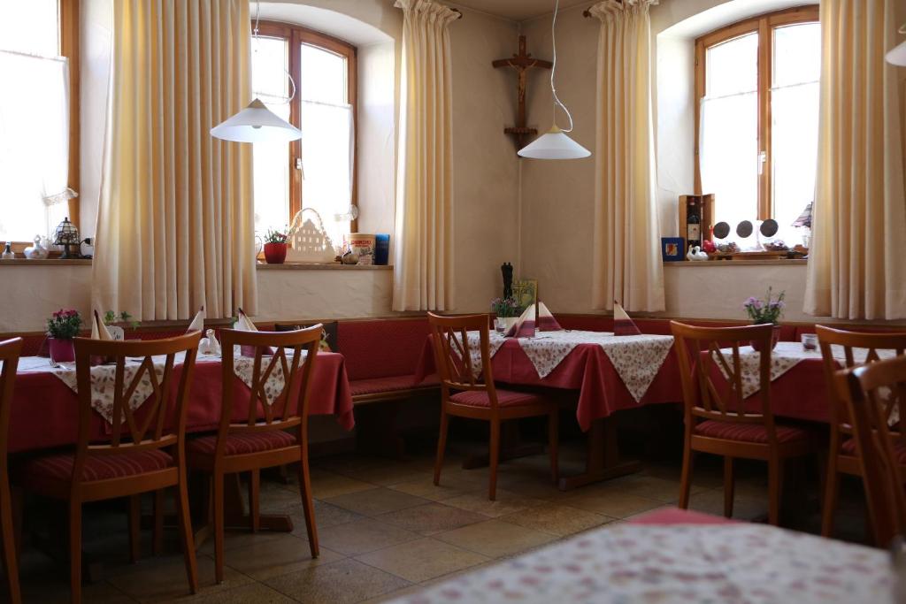 un comedor con mesas, sillas y ventanas en Genießerhotel Limbacher en Herrieden