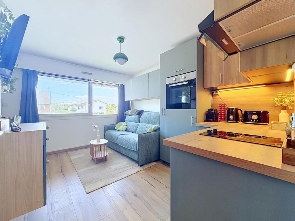 a kitchen and a living room with a couch at Stella Plage, Studio Vert et Mer in Cucq