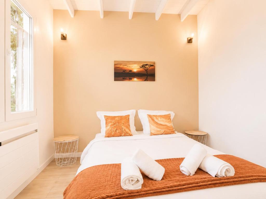 a bedroom with a bed with white sheets and orange pillows at Road Stop Studio - Paris - Disney- Train Station in Chelles