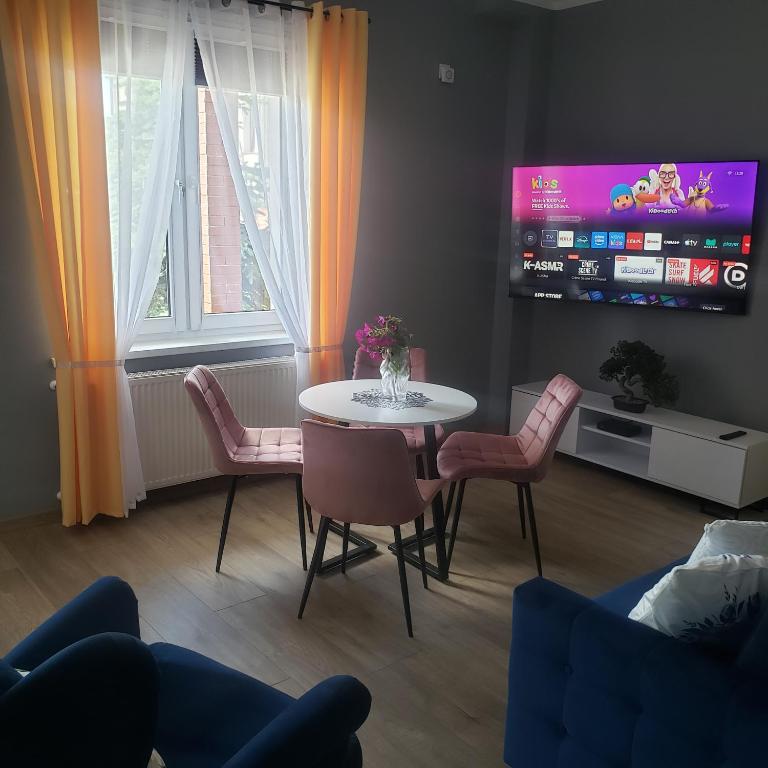 a living room with a table and chairs and a tv at Apartamenty AGA13 in Mikołajki