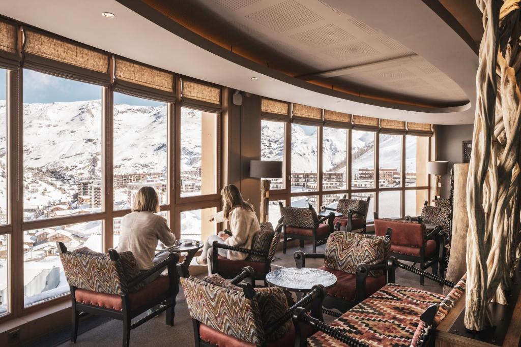 two women sitting at a table in a room with a mountain view at Le Taos in Tignes