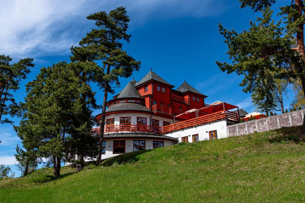 a red building on top of a hill at Hotel VÍTKOVA HORA in Karlovy Vary