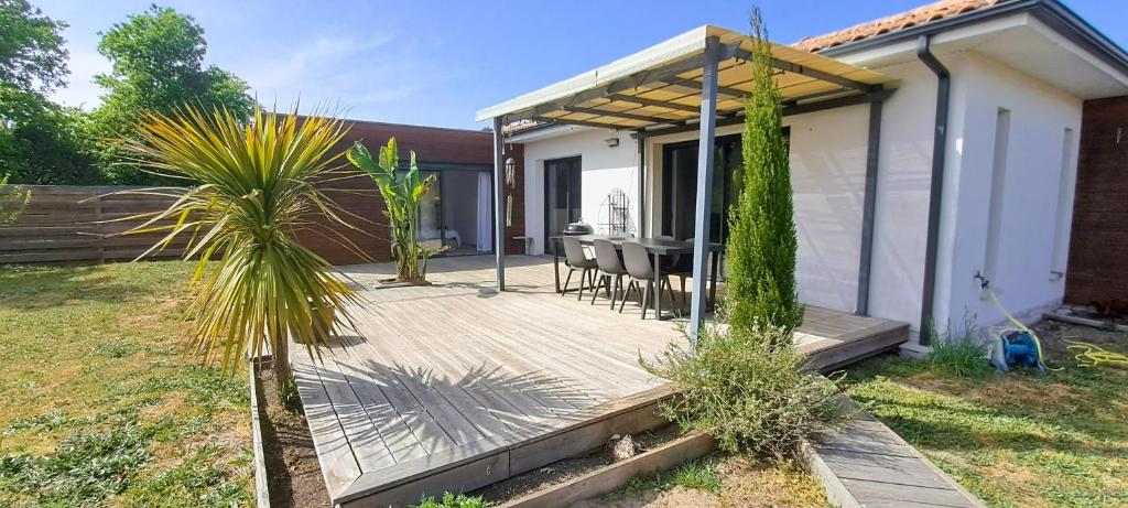 a wooden deck with a table and chairs in a yard at L'expérience quiétude espace modernité à Salles in Salles
