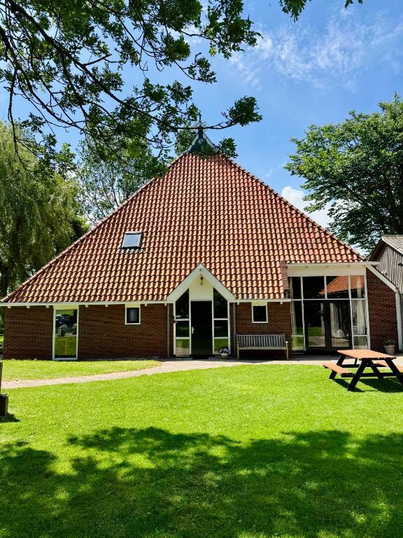a building with a red roof and a picnic table at De Gelukskever renovated 2024 in Hindeloopen
