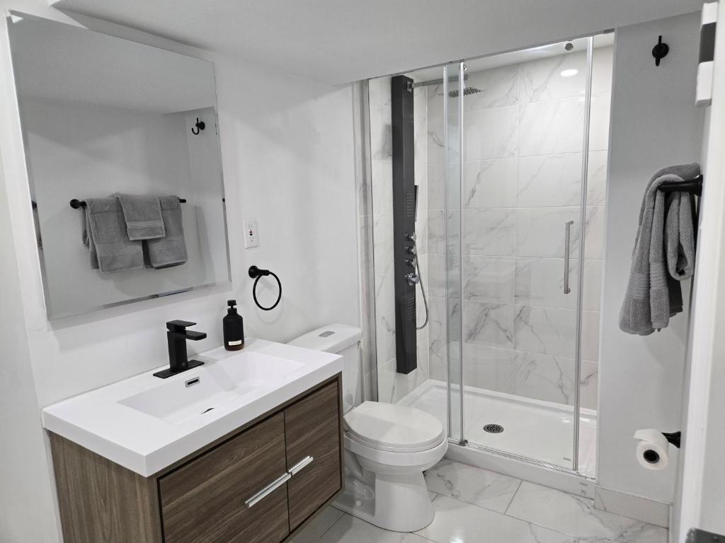 a white bathroom with a toilet and a shower at Private Entry-Modern & Bright Longueuil Suite in Longueuil