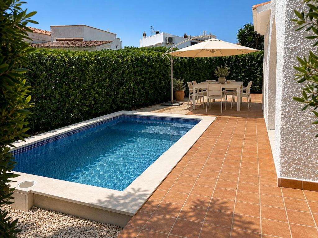 a swimming pool with a table and an umbrella at Villa Gabriela in S'Algar
