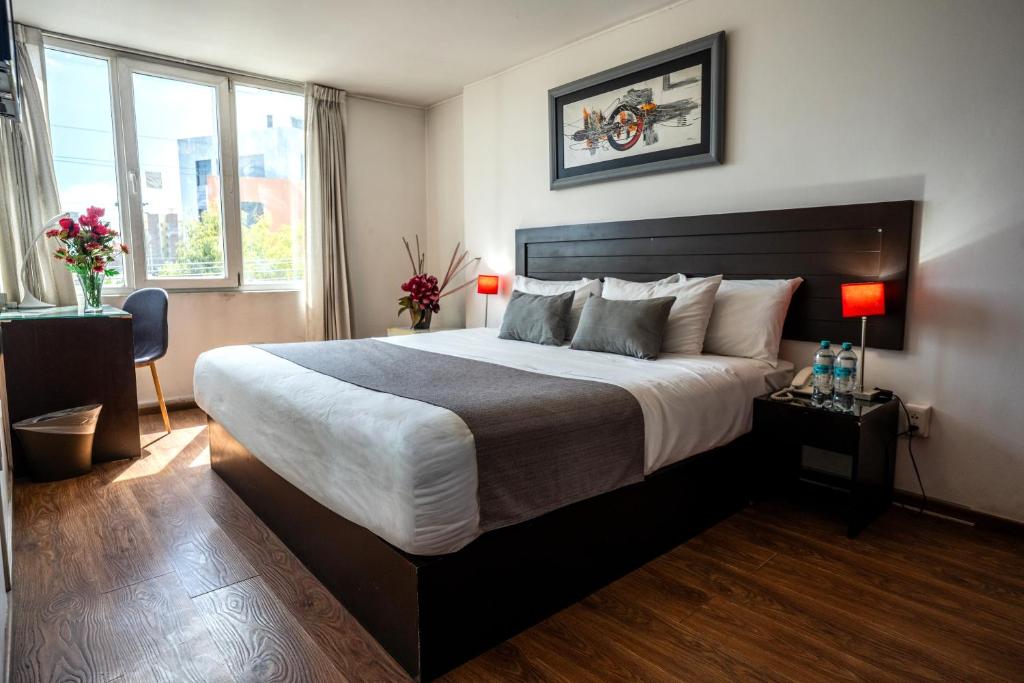 a bedroom with a large bed and two windows at Hoteles Riviera Ejecutivo in Arequipa