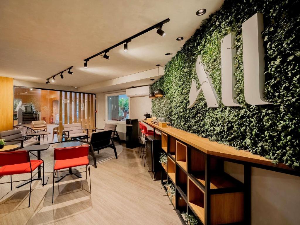 a restaurant with a green wall with tables and chairs at ibis Sao Paulo Congonhas in São Paulo