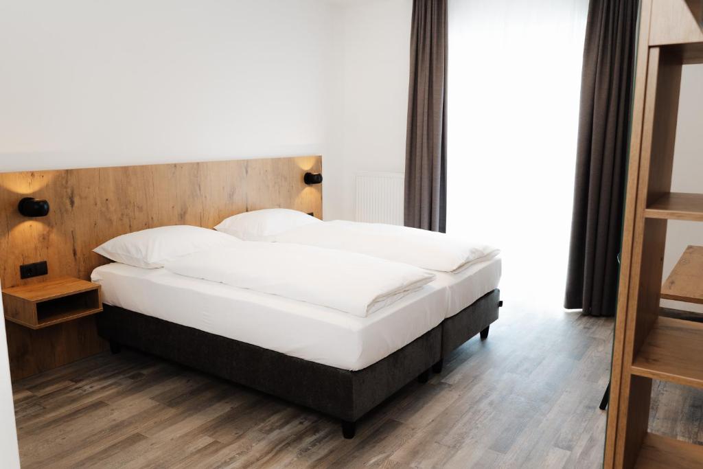 a bedroom with a bed with a wooden headboard at ML Business Hotel - Self-Check-in in Lannach
