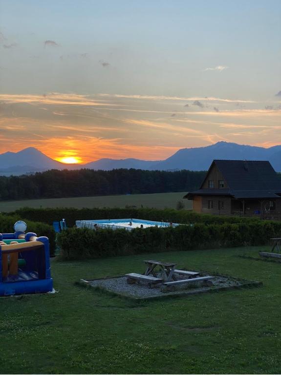 a sunset in a yard with a pool and a house at Víkendové Chalupy in Liptovský Trnovec