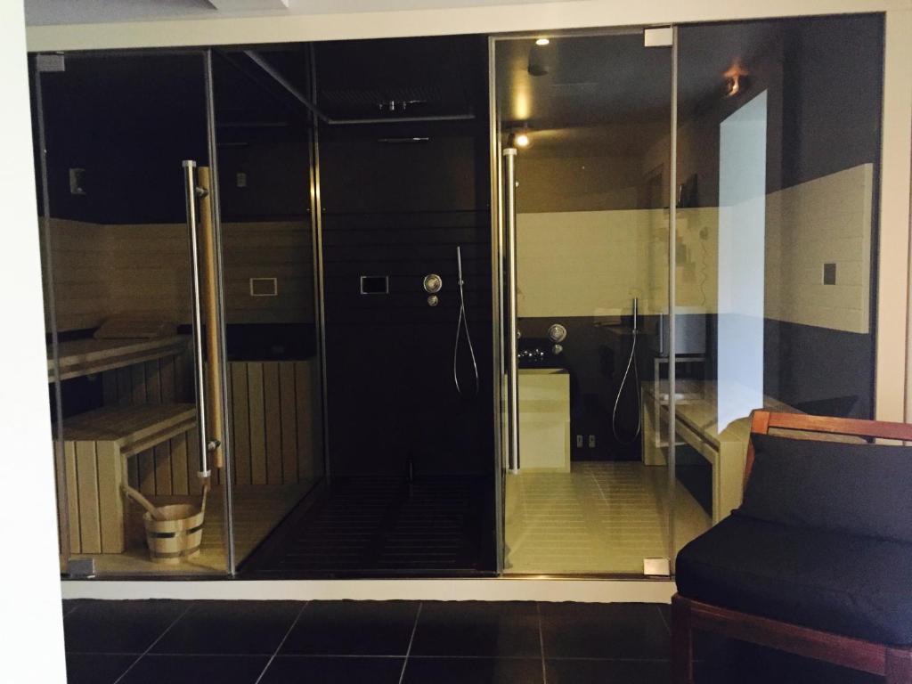 a glass shower in a room with a couch at Hôtel du Bout du Monde in Saint-Flour