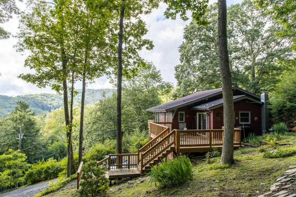 a cabin in the woods with a wrap around deck at A Red Chalet in Newland