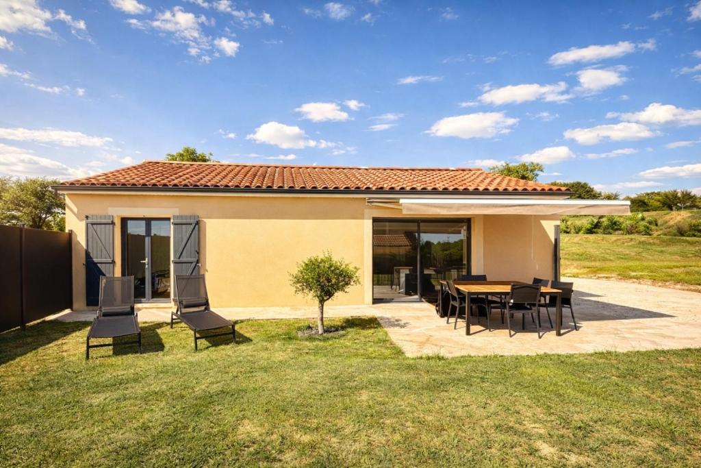 a house with a patio and a table and chairs at Maison Neuve Climatisée in Carlux