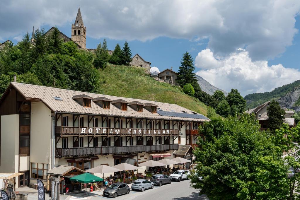 a building on a hill with cars parked in the street at Hotel Castillan in La Grave