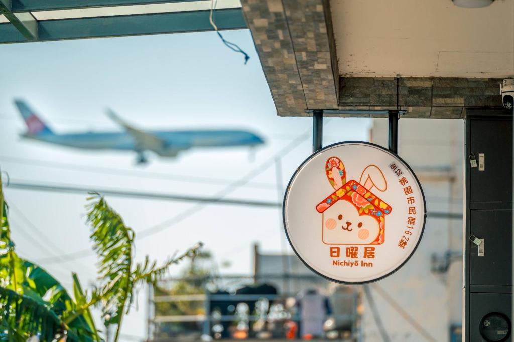 a sign hanging from a building with an airplane in the sky at 日曜居Nichiyō inn in Dayuan