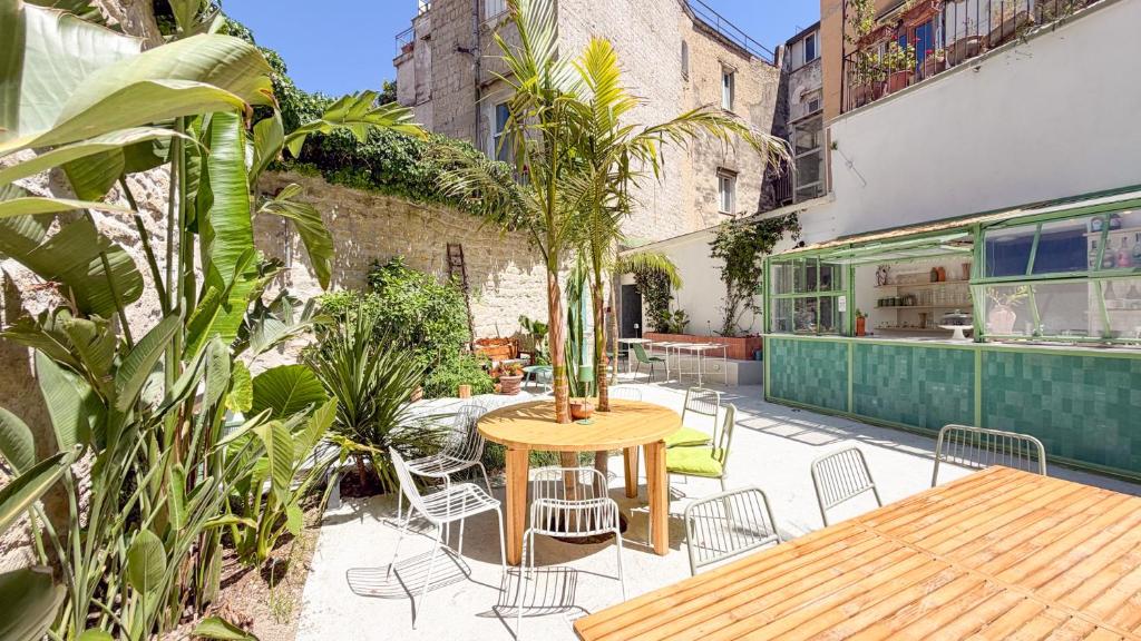 an outdoor patio with a wooden table and chairs at OSA - Stella - Garden Hostel with bar in Naples