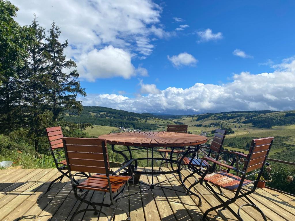a table and chairs on a deck with a view at Bastide en Margeride in Châteauneuf-de-Randon