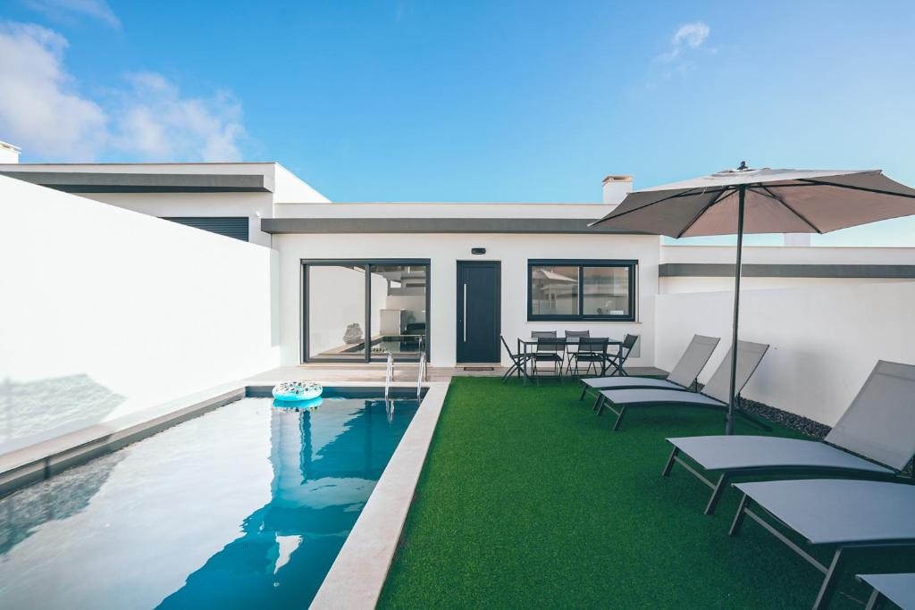 a swimming pool with chairs and an umbrella at Villa Delfina with private pool in Mariquiteira