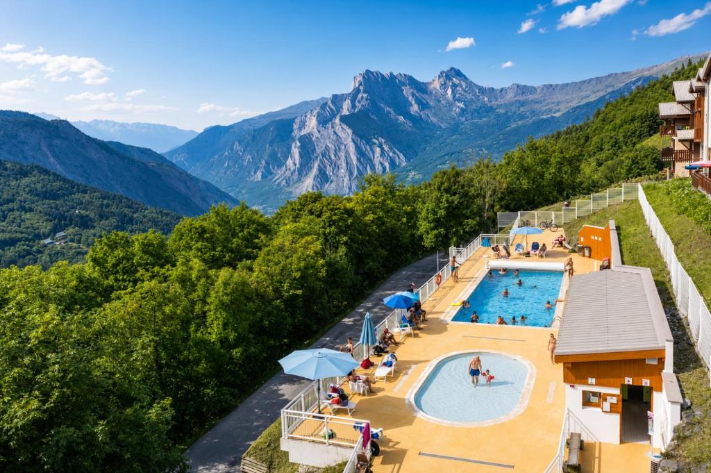 a hotel with a pool and mountains in the background at Village vacances de Valmeinier "Les Angeliers" in Valmeinier