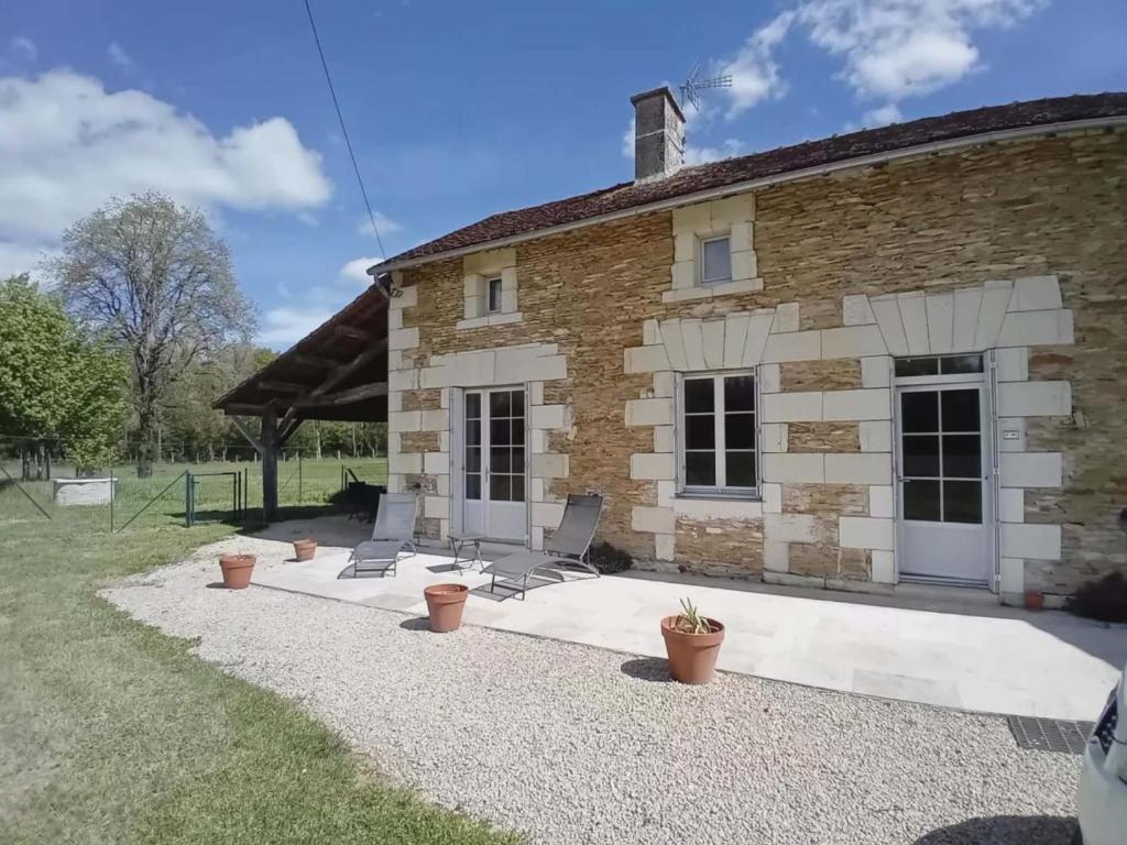 a stone house with chairs in front of a building at Le petit scevolles in Verrue