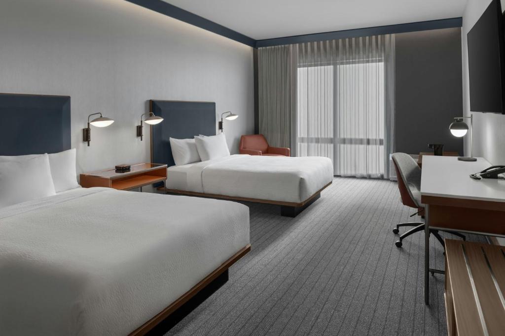a hotel room with two beds and a desk at Courtyard by Marriott Woodland in Woodland