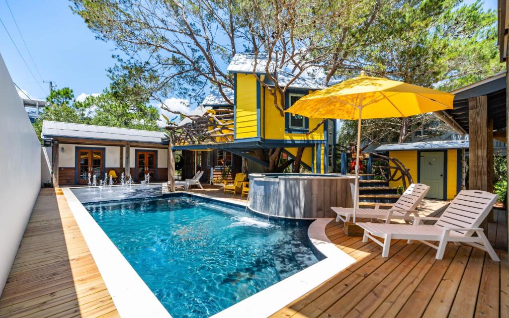 a pool with chairs and an umbrella next to a house at Tickle Me Tides in Inlet Beach