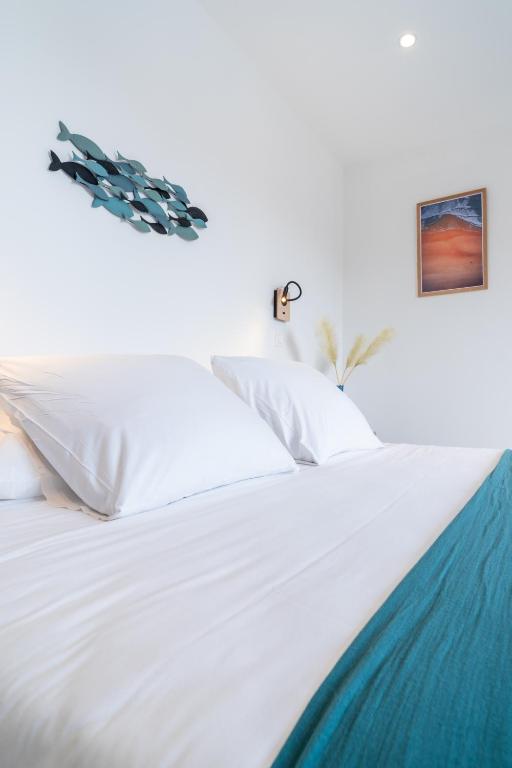 a white bed with white sheets and pillows at Hôtel La Chaumière-Les Pastourelles in Capbreton